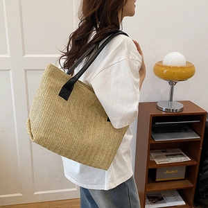 Minimalist woven straw tote bag with black leather straps for summer casual style