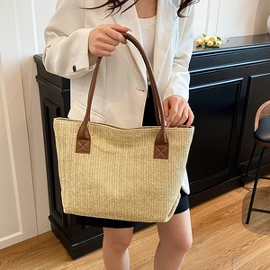 Minimalist woven straw tote bag with brown leather handles for summer vacation fashion