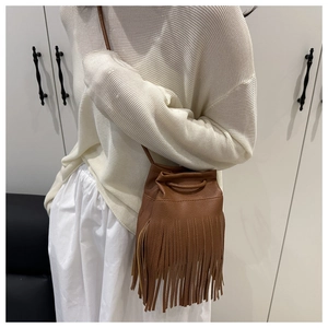 Gros plan d'un sac seau marron à franges montrant le cuir grainé et les détails de glands