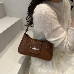 Brown faux crocodile leather underarm bag with a silver star buckle on white stairs