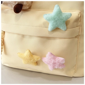 Detailed macro view of beige canvas backpack featuring cute colorful plush star ornaments