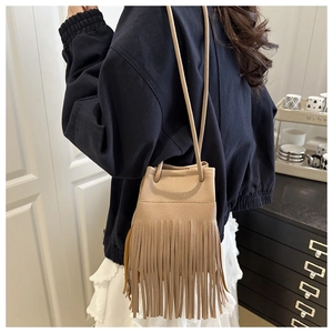Détail du sac seau beige en similicuir montrant de longues franges et un cordon de serrage