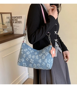 Detailed texture of blue floral fabric underarm bag with pink chain strap and flower charm