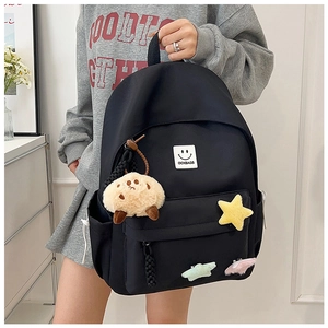 Close-up of lightweight black school backpack with cute plush monster and star charms