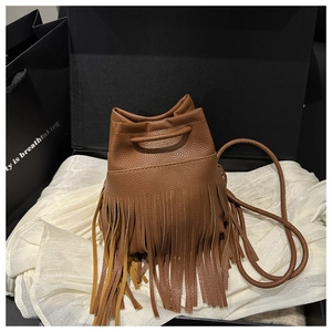 Gros plan du sac seau marron caramel avec texture en cuir grainé et longues franges