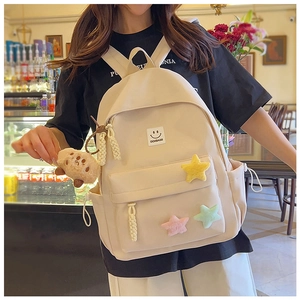 Detail of beige campus backpack with colorful plush star patches and bear keychain