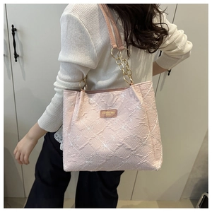 Detail of light pink tote bag featuring floral embroidery and quilted chain strap on model