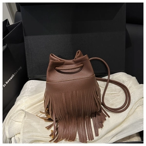 Détail d'un sac seau en cuir marron foncé avec franges bohèmes et cordon de serrage