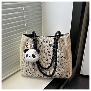 Close-up of woven tote bag with panda pendant and graffiti patterns near the window