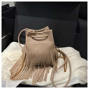 Détail du sac seau beige à franges en cuir présenté dans un coffret cadeau de luxe