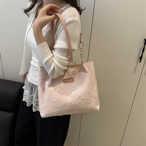 Borsa tote rosa con ricami floreali e catena dorata indossata a spalla dal modello