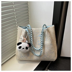 Detailed close-up of woven tote bag with blue floral patterns and panda plush charm