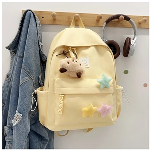Close-up of cream yellow backpack featuring plush star patches and a cute smiley face logo