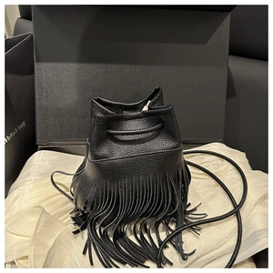 Détail d'un sac seau en cuir noir avec de longues franges et une fermeture à cordon