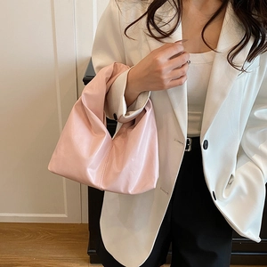 Pink pleated dumpling tote bag carried by a model in a stylish business casual outfit