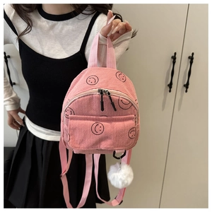 Pink corduroy backpack with black smile patterns and a plush ball charm detail