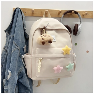 Detail of cream backpack with plush stars and brown bear charm on wooden hook