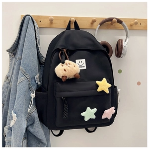 Detail of black nylon backpack featuring OXBAGS logo patch and plush star pendant charm