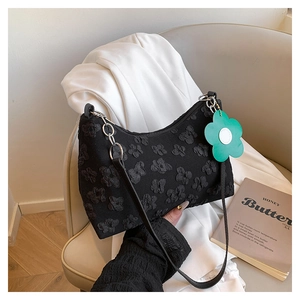 Detail of black floral jacquard shoulder bag with green flower charm and silver chain