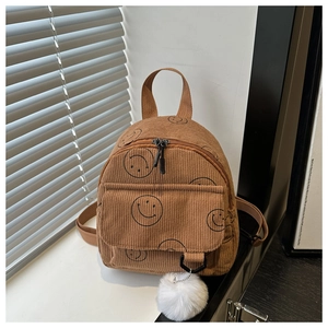 Detailed close-up of brown corduroy backpack with smiley prints and white fur ball