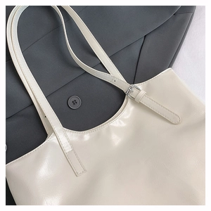 Detail of soft cream leather tote bag featuring a silver metal buckle and adjustable strap