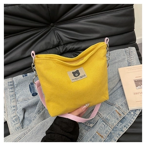Detail of yellow corduroy tote bag with Myron Bear patch and pink leather strap