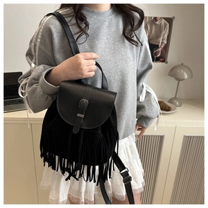 Detailed view of black tassel backpack with metallic buckle in a lifestyle setting