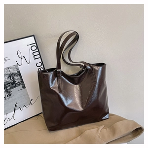 Detail of dark brown glossy wax leather tote bag texture with slim shoulder straps