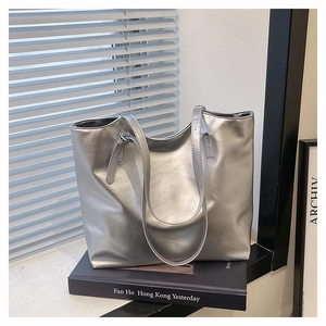 Detail view of silver metallic leather texture and slim shoulder straps on a large tote bag