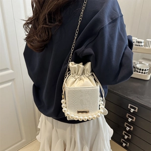 White snakeskin bucket bag with large pearl handle and gold chain strap for women