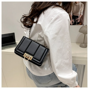 Detail of black quilted leather shoulder bag with gold horseshoe buckle and chain strap