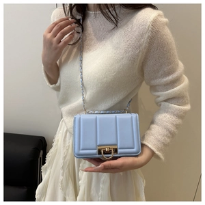 Fashionable light blue quilted chain crossbody bag shown on a model in a modern room