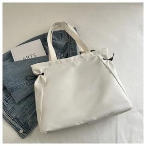 Detailed view of a white minimalist tote bag with side black drawstring adjustment clips