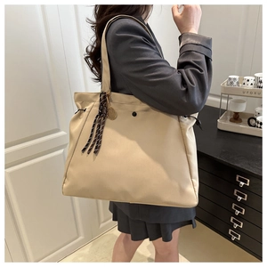Lifestyle shot of large khaki tote bag with drawstring details and metal tennis pendant