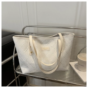 Modern white canvas tote bag with woven texture on a silver stand in a chic cafe setting