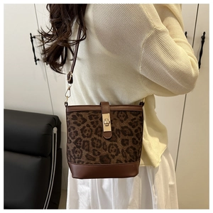 Détail du sac seau à imprimé léopard avec base en cuir marron et fermoir doré en métal