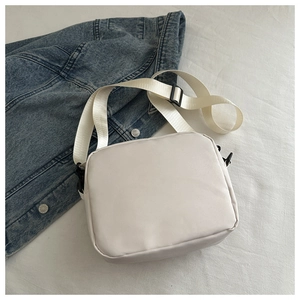 Detailed view of white nylon shoulder bag featuring adjustable strap and smooth texture