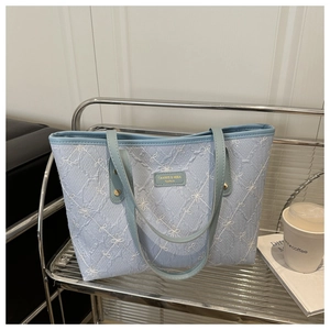Detail shot of blue floral embroidery and grid pattern on large capacity tote bag