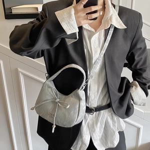 Silver bow hobo bag with glossy finish and adjustable strap shown in a mirror selfie