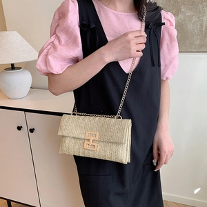 Vintage straw crossbody bag with golden chain and metallic buckle worn by a model