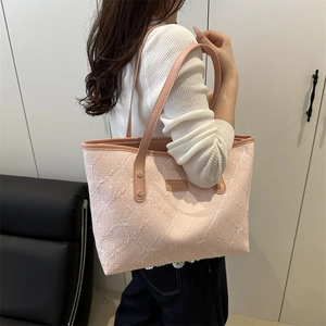 Pink quilted tote bag with floral bow texture shown from side-back on female model
