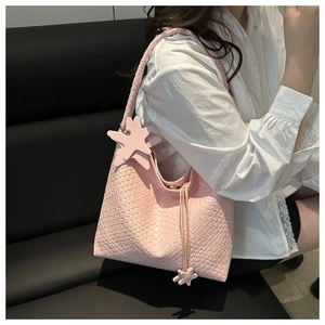 Détail d'un sac seau tissé rose avec des charms étoiles et cordon de serrage