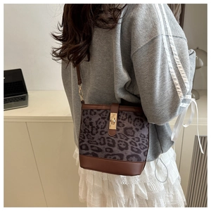 Détail du sac seau léopard tendance avec bordure en cuir marron et fermoir doré rotatif