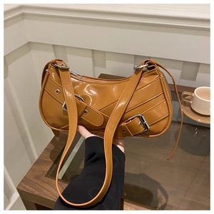 Close-up of caramel glossy leather bag with decorative silver metal buckles and straps