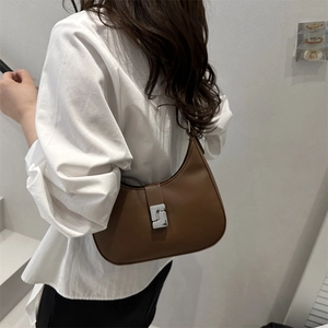 Minimalist coffee brown saddle hobo bag with geometric silver buckle on model's shoulder