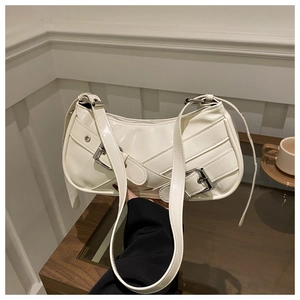 Detail of white glossy baguette bag featuring silver metal buckles and adjustable strap