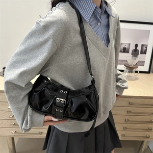 Ruched black patent leather shoulder bag with vintage silver buckle shown on shoulder