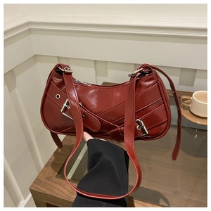 Detail of burgundy baguette bag in glossy finish with stylish buckle straps and silver hardware