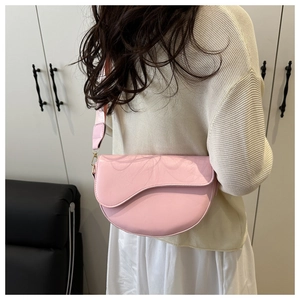 Detailed back view of pink faux leather saddle bag with wide shoulder strap and gold hardware