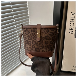 Détail du sac seau à imprimé léopard avec bordure en cuir marron et fermoir doré